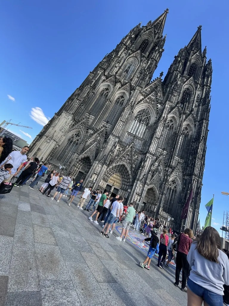 The twin Gothic spires of the west front rising steeply over a crowd on the cathedral square.